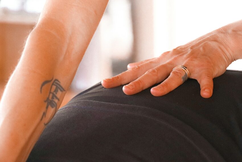 Hand resting on person's lower back during massage.